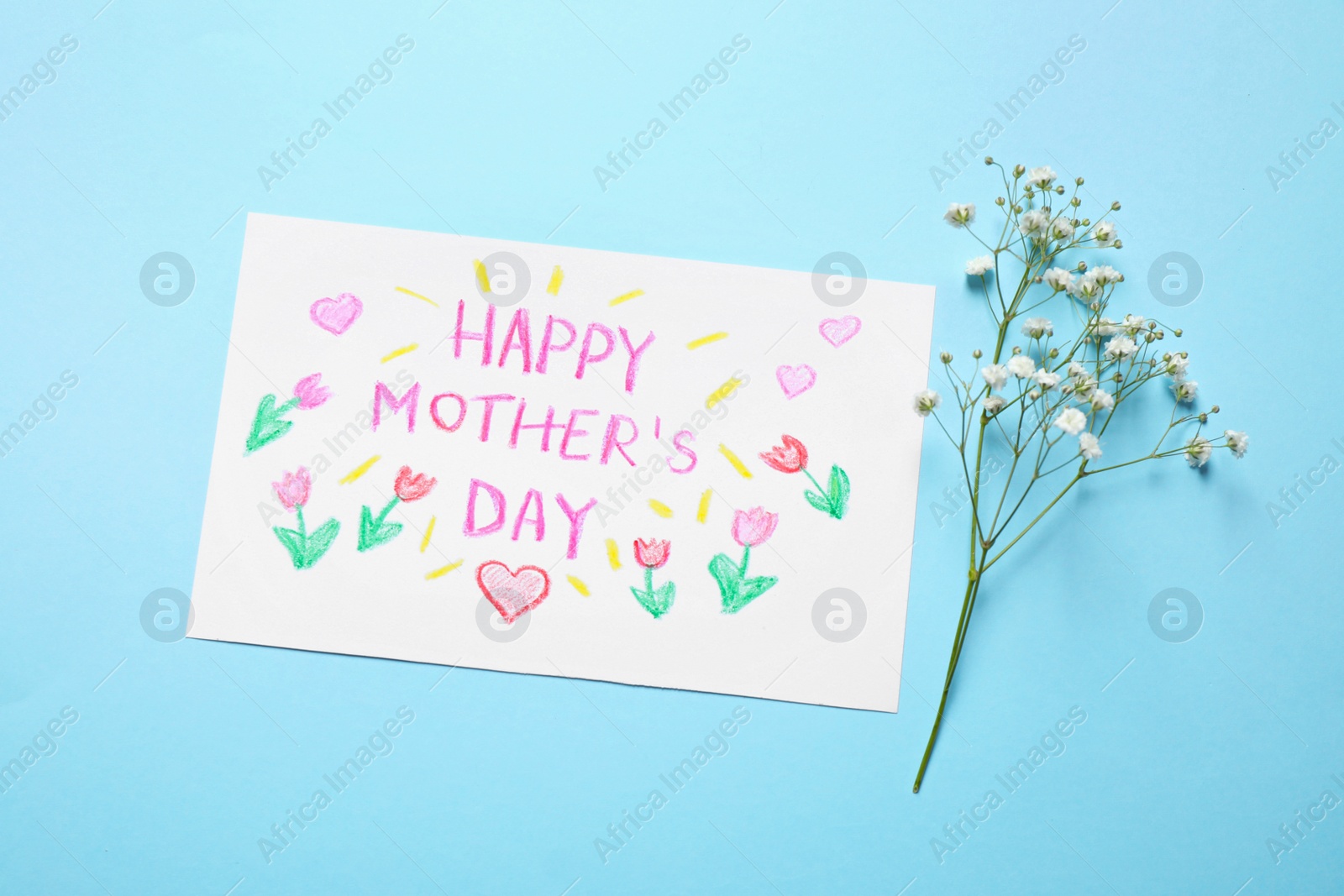 Photo of Handmade greeting card for Mother's day and flower on light blue background, flat lay