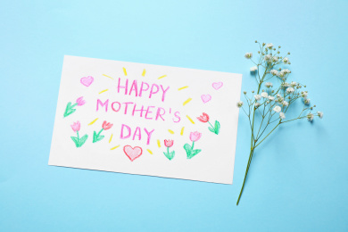 Handmade greeting card for Mother's day and flower on light blue background, flat lay Photo of Handmade greeting card for Mother's day and flower on light blue background, flat lay