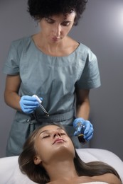 Cosmetologist applying serum on client's face in salon Photo of Cosmetologist applying serum on client's face in salon