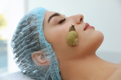 Young woman receiving snail facial massage in spa salon, closeup Photo of Young woman receiving snail facial massage in spa salon, closeup