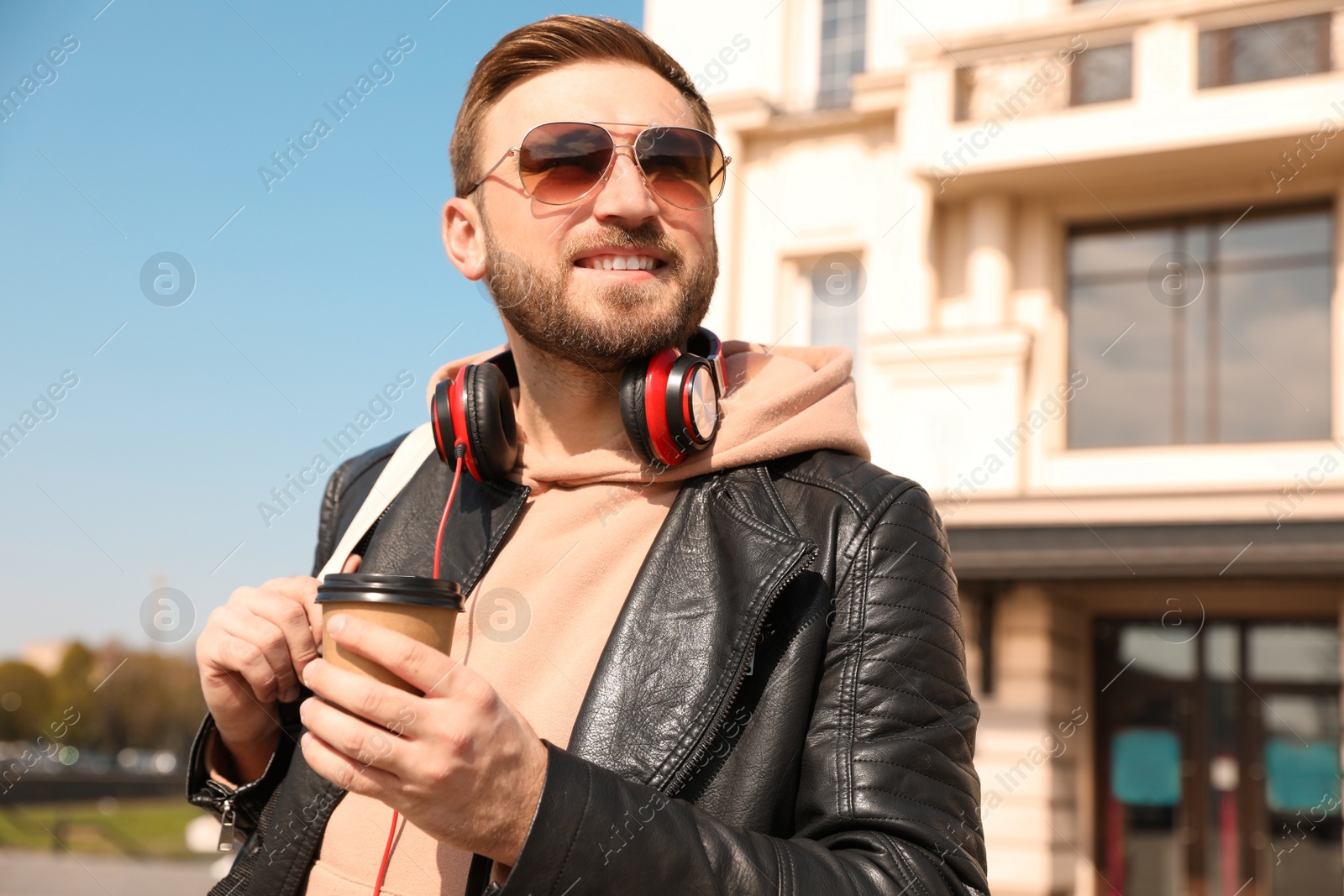 Happy young man with coffee on city street in morning Photo of Happy young man with coffee on city street in morning