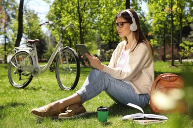 Woman with headphones and tablet working in park Photo of Woman with headphones and tablet working in park