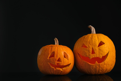 Pumpkins with scary faces on black background. Halloween traditional decor Photo of Pumpkins with scary faces on black background. Halloween traditional decor