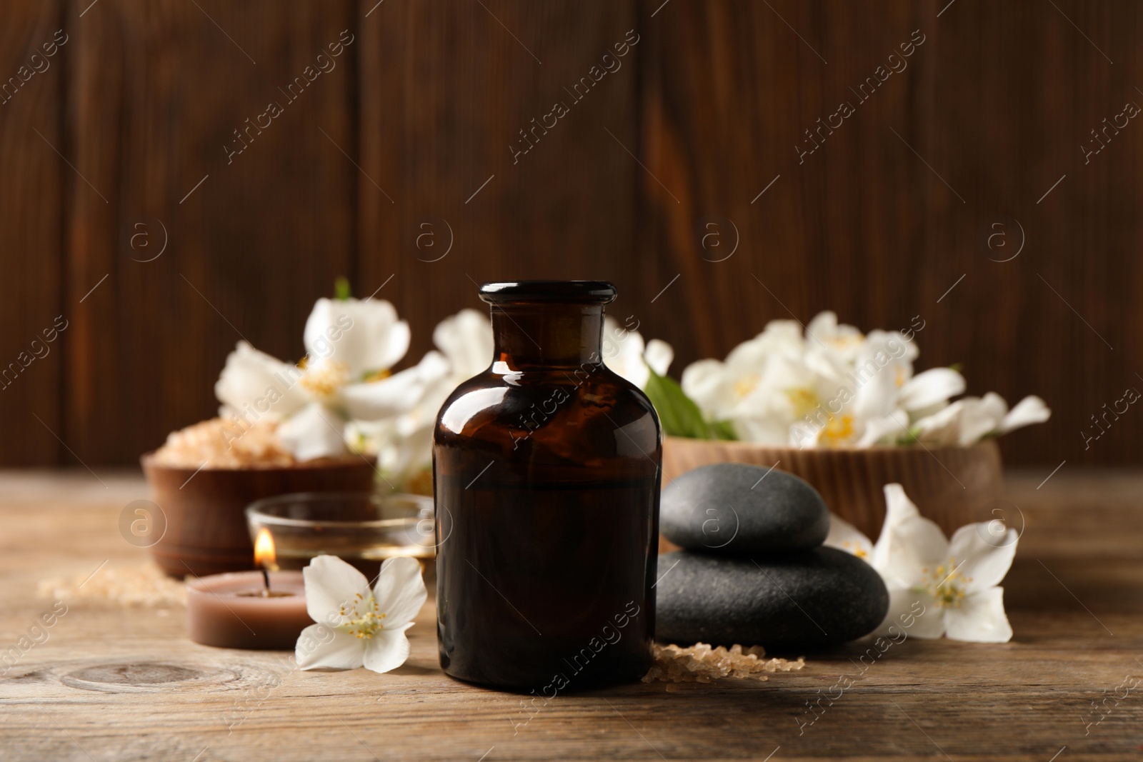 Beautiful composition with jasmine essential oil and fresh flowers on wooden table Photo of Beautiful composition with jasmine essential oil and fresh flowers on wooden table