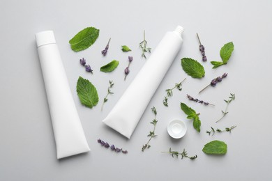 Blank tubes of toothpaste, mint, thyme and lavender flowers on white background, flat lay Photo of Blank tubes of toothpaste, mint, thyme and lavender flowers on white background, flat lay