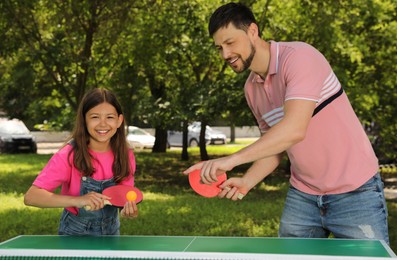 Happy man with his daughter playing ping pong in park Photo of Happy man with his daughter playing ping pong in park
