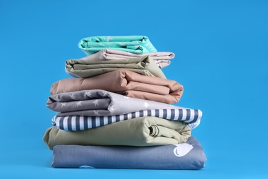 Stack of clean bed sheets on blue background Photo of Stack of clean bed sheets on blue background
