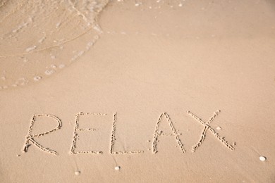 Word Relax written on sand at beach Photo of Word Relax written on sand at beach