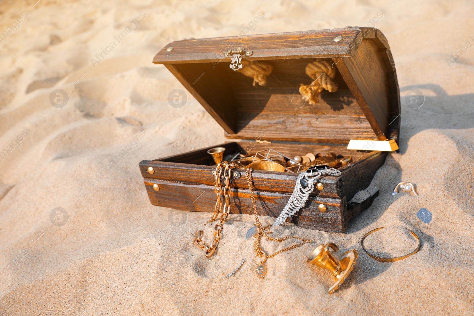 Open wooden treasure chest on sand, space for text Photo of Open wooden treasure chest on sand, space for text