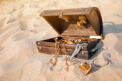 Open wooden treasure chest on sand, space for text Photo of Open wooden treasure chest on sand, space for text