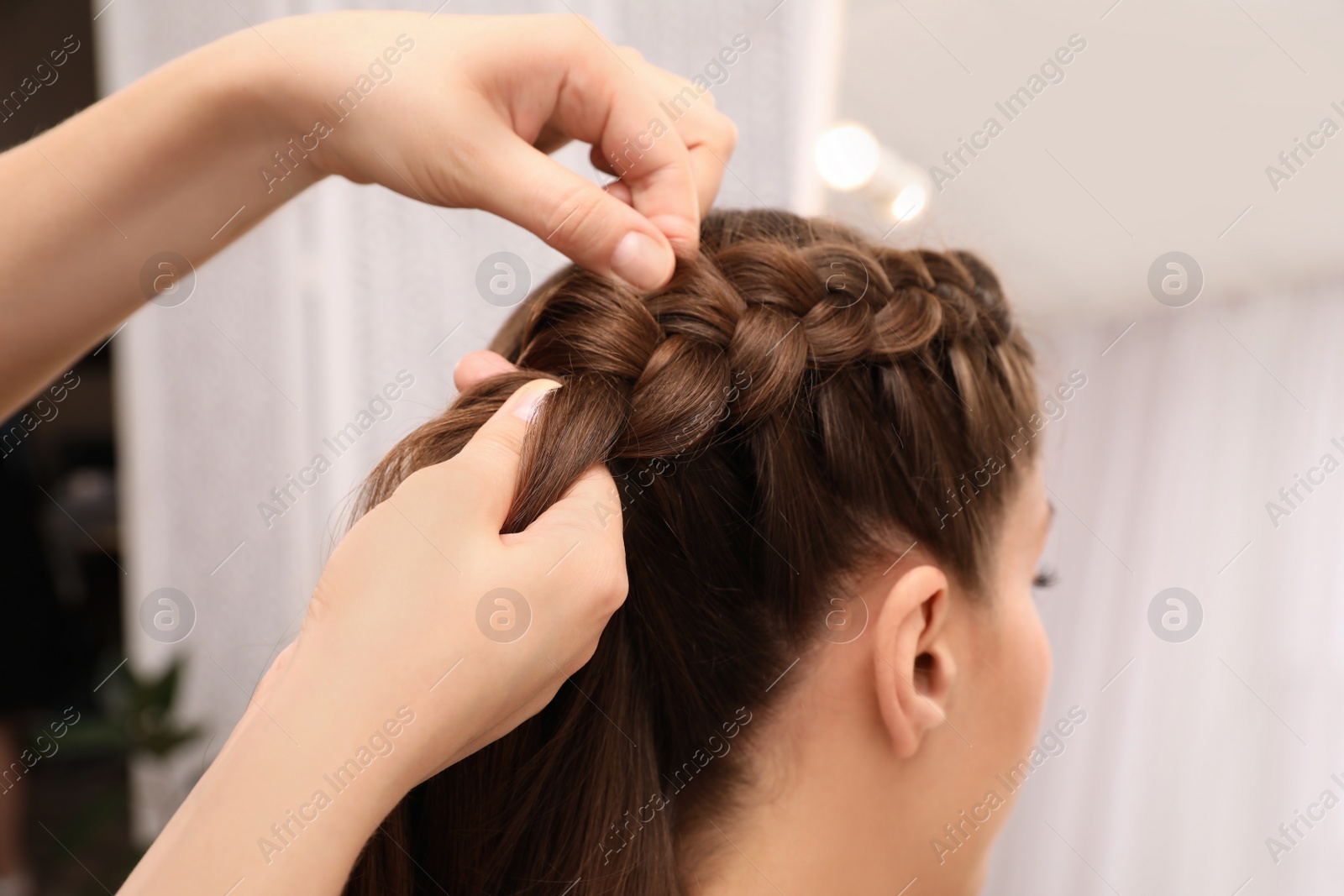 Professional stylist braiding client's hair in salon, closeup Photo of Professional stylist braiding client's hair in salon, closeup