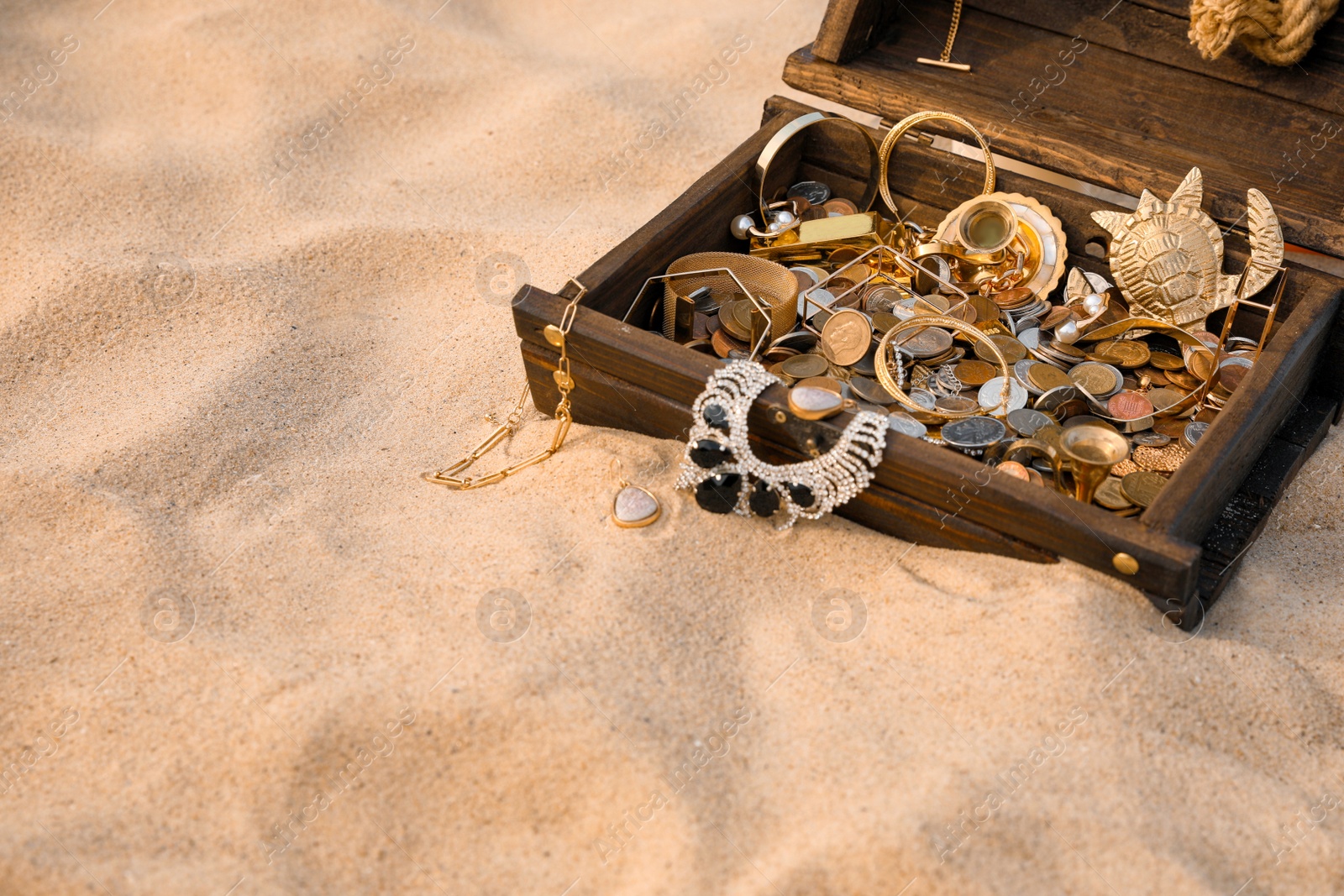 Open wooden treasure chest on sand, space for text Photo of Open wooden treasure chest on sand, space for text