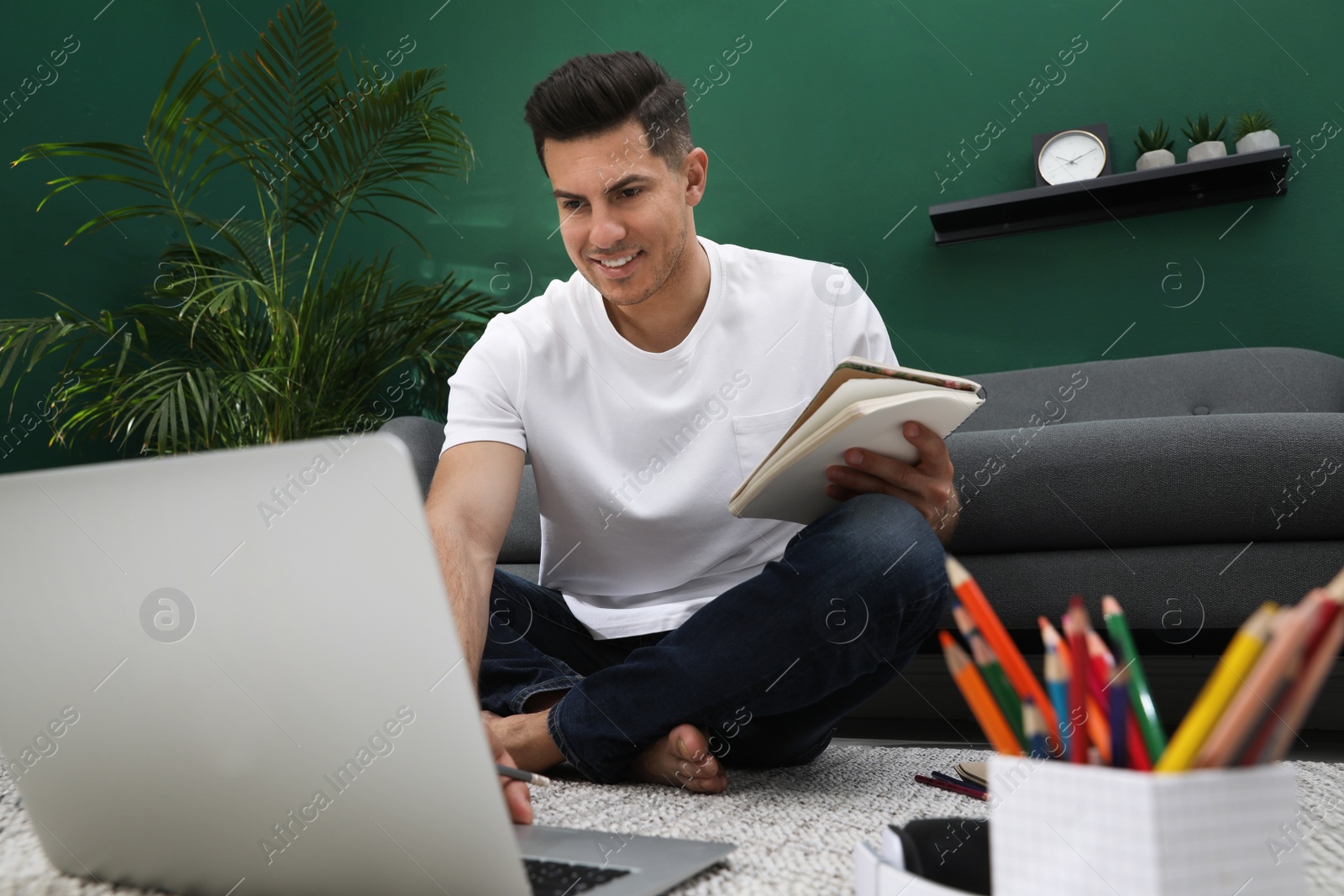 Man drawing in notebook at online lesson indoors. Distance learning Photo of Man drawing in notebook at online lesson indoors. Distance learning