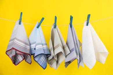 Many different handkerchiefs hanging on rope against yellow background Photo of Many different handkerchiefs hanging on rope against yellow background