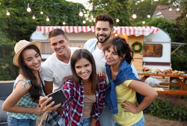 Happy friends taking selfie near trailer. Camping season Photo of Happy friends taking selfie near trailer. Camping season