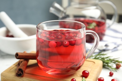 Tasty hot cranberry tea and fresh ingredients on table Photo of Tasty hot cranberry tea and fresh ingredients on table