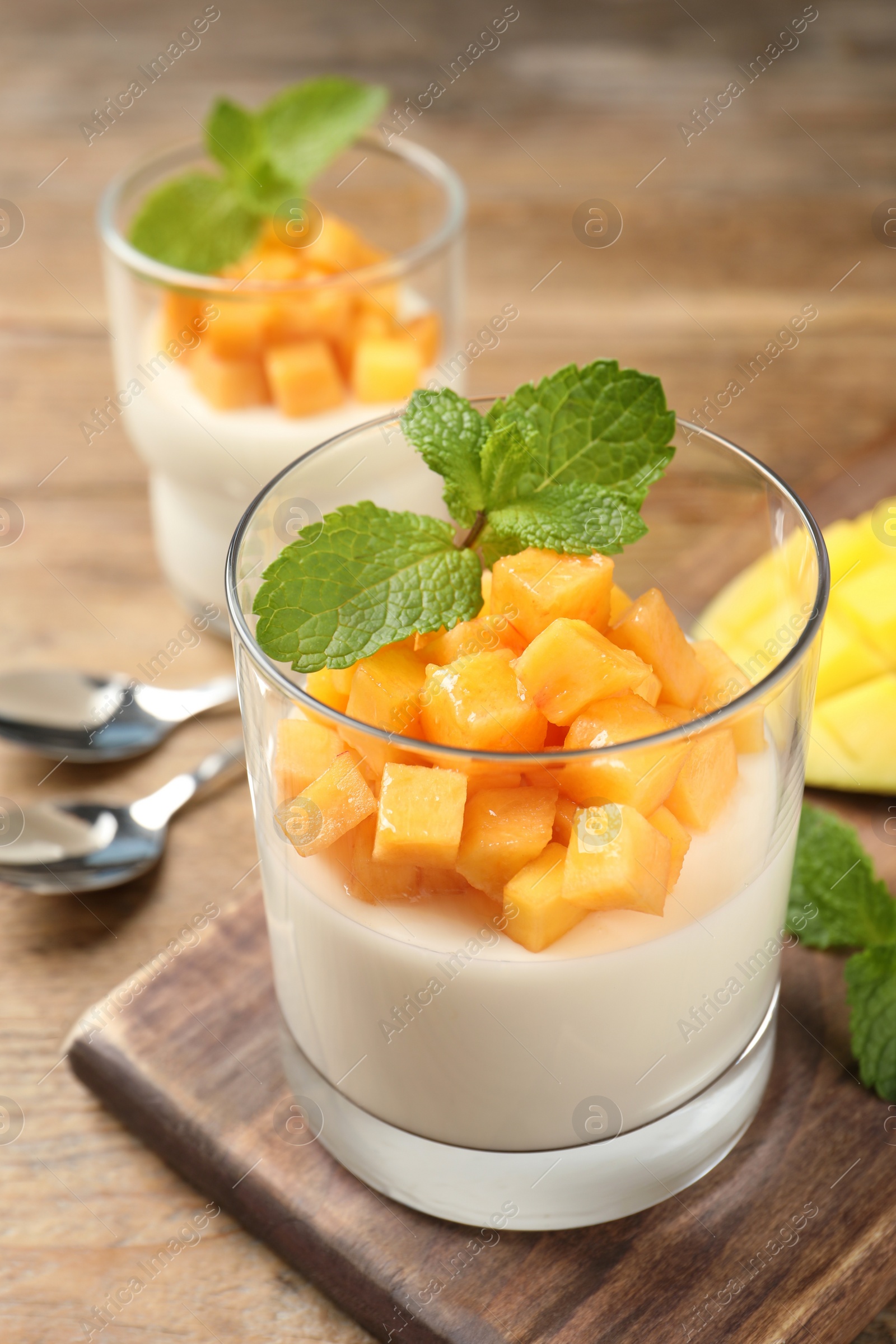 Delicious panna cotta with mango on wooden table Photo of Delicious panna cotta with mango on wooden table