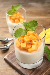 Delicious panna cotta with mango on wooden table Photo of Delicious panna cotta with mango on wooden table