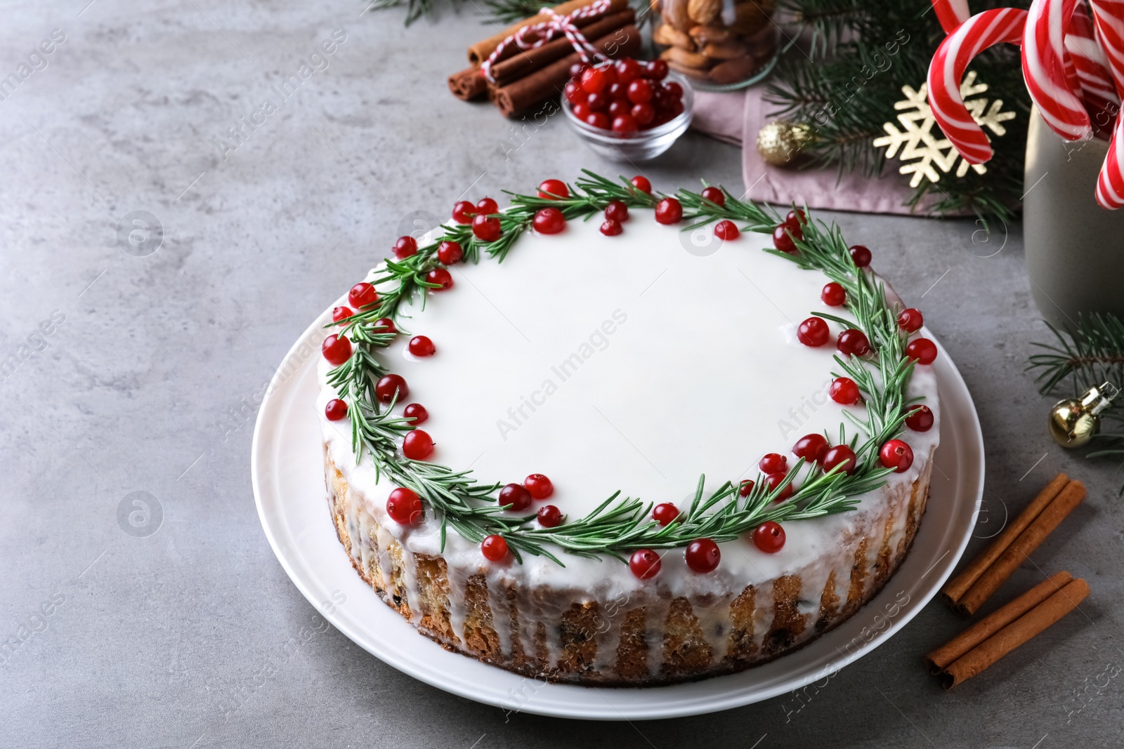 Photo of Traditional Christmas cake decorated with rosemary and cranberries on light grey table