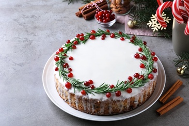 Photo of Traditional Christmas cake decorated with rosemary and cranberries on light grey table