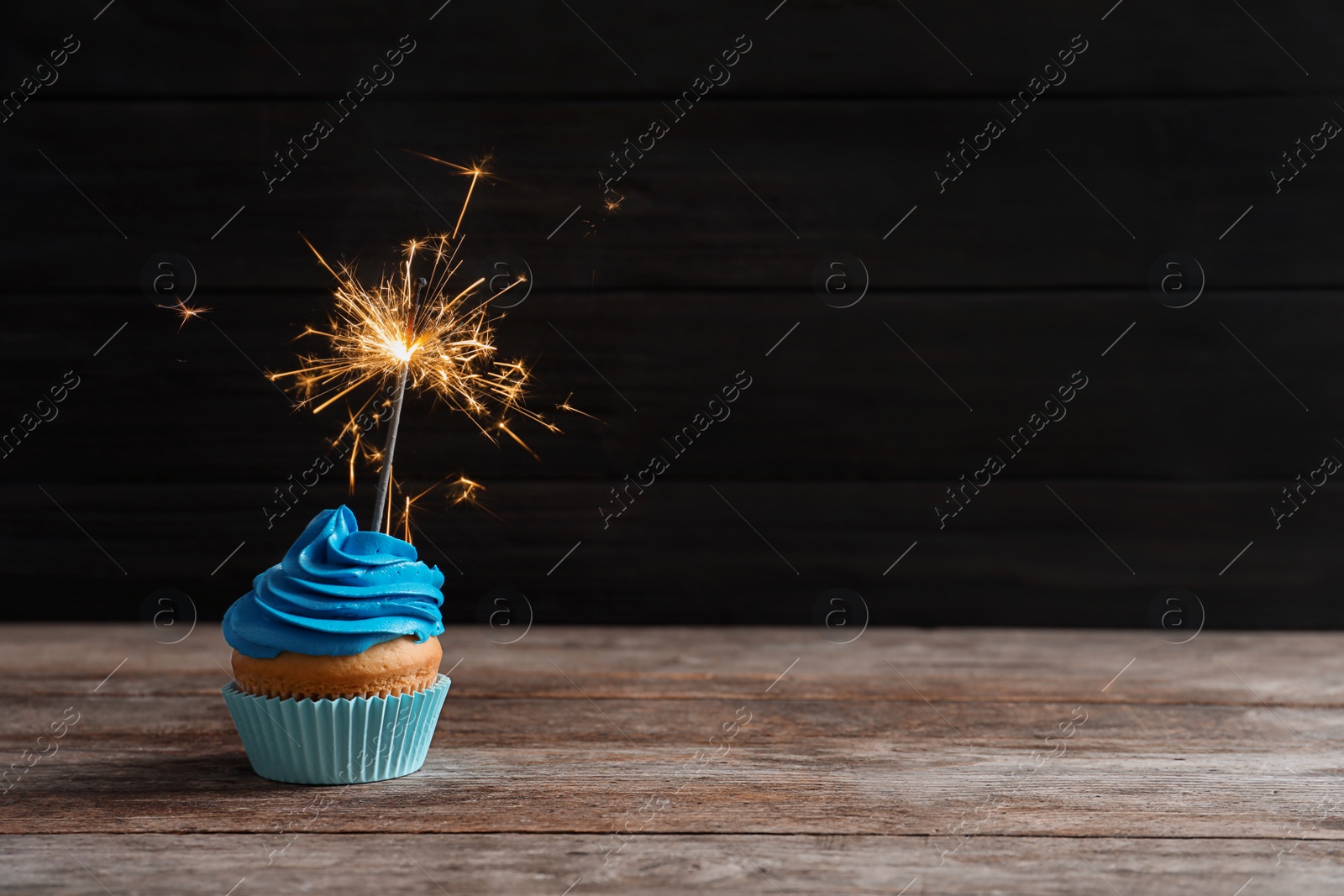 Delicious birthday cupcake with sparkler on table Photo of Delicious birthday cupcake with sparkler on table
