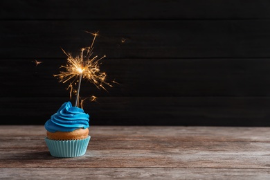 Delicious birthday cupcake with sparkler on table Photo of Delicious birthday cupcake with sparkler on table