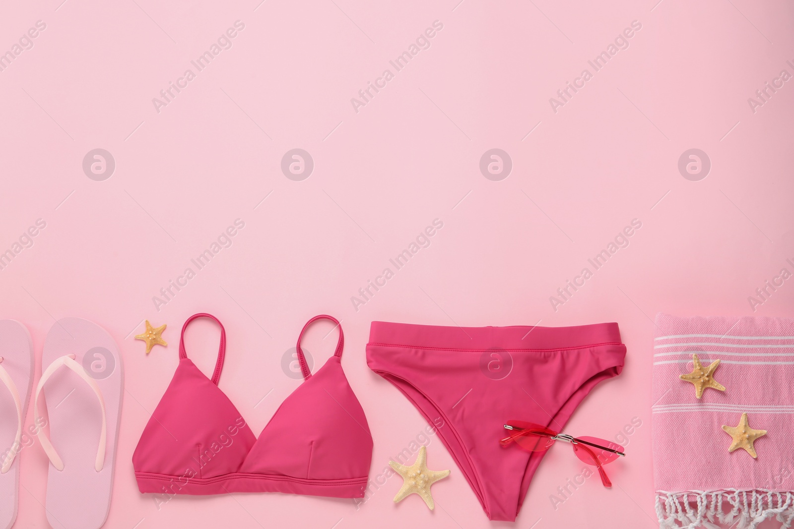 Photo of Stylish bikini and beach accessories on pink background, flat lay. Space for text