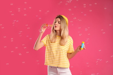 Young woman blowing soap bubbles on pink background Photo of Young woman blowing soap bubbles on pink background
