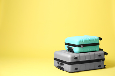 Photo of Stylish suitcases on yellow background. Space for text