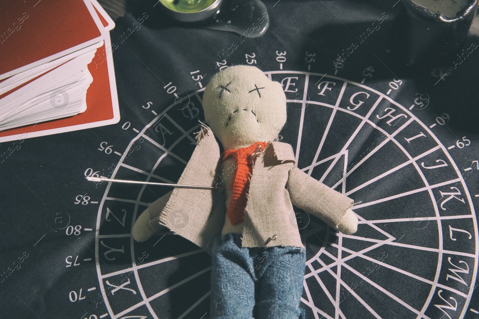 Voodoo doll pierced with needle on table. Curse ceremony Photo of Voodoo doll pierced with needle on table. Curse ceremony