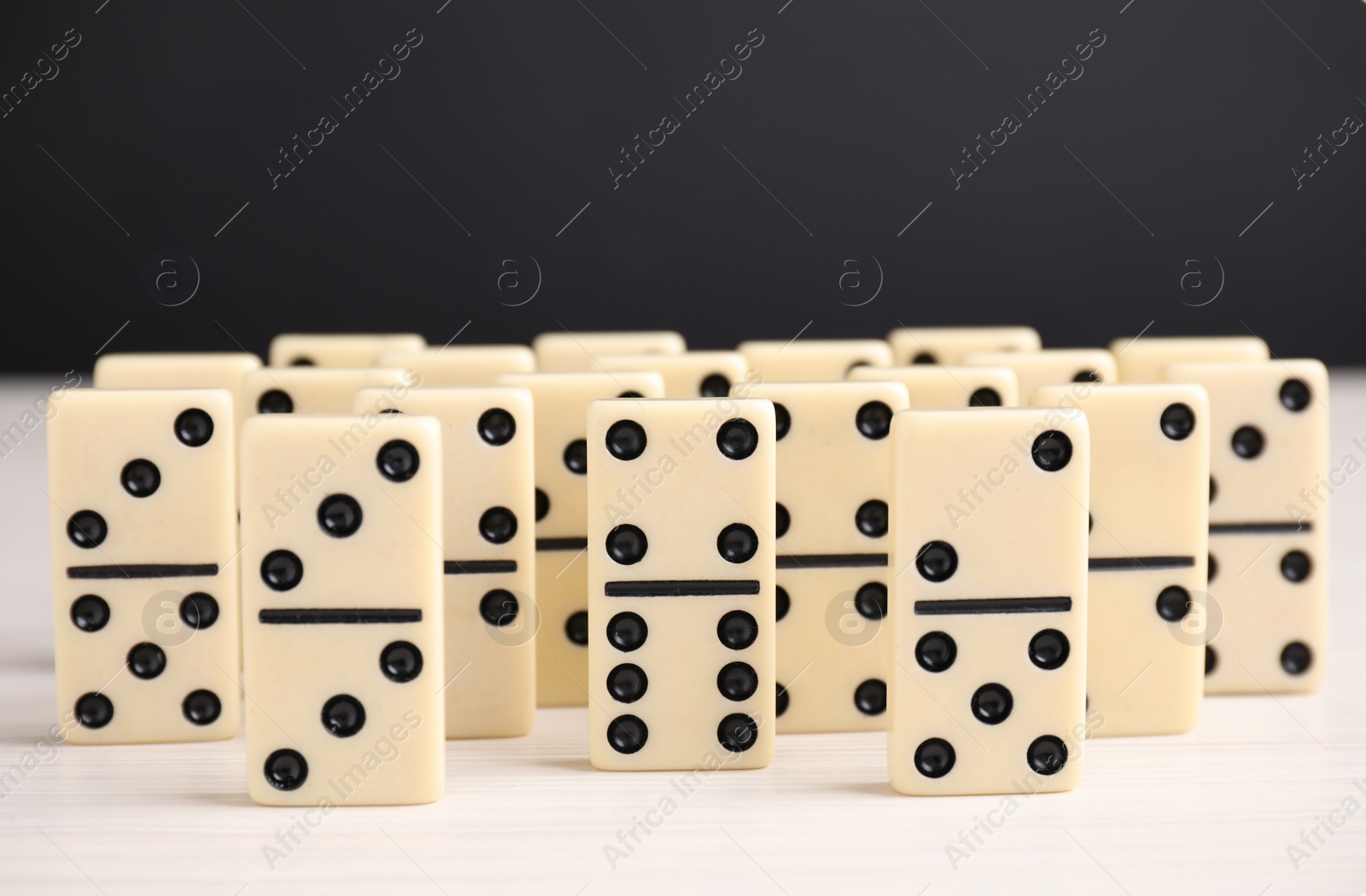 Domino tiles on wooden table against black background Photo of Domino tiles on wooden table against black background
