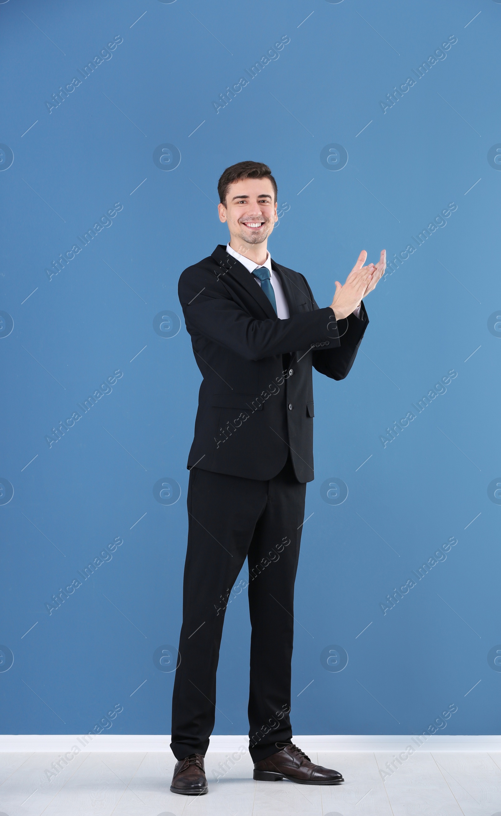 Business trainer applauding on color wall background Photo of Business trainer applauding on color wall background