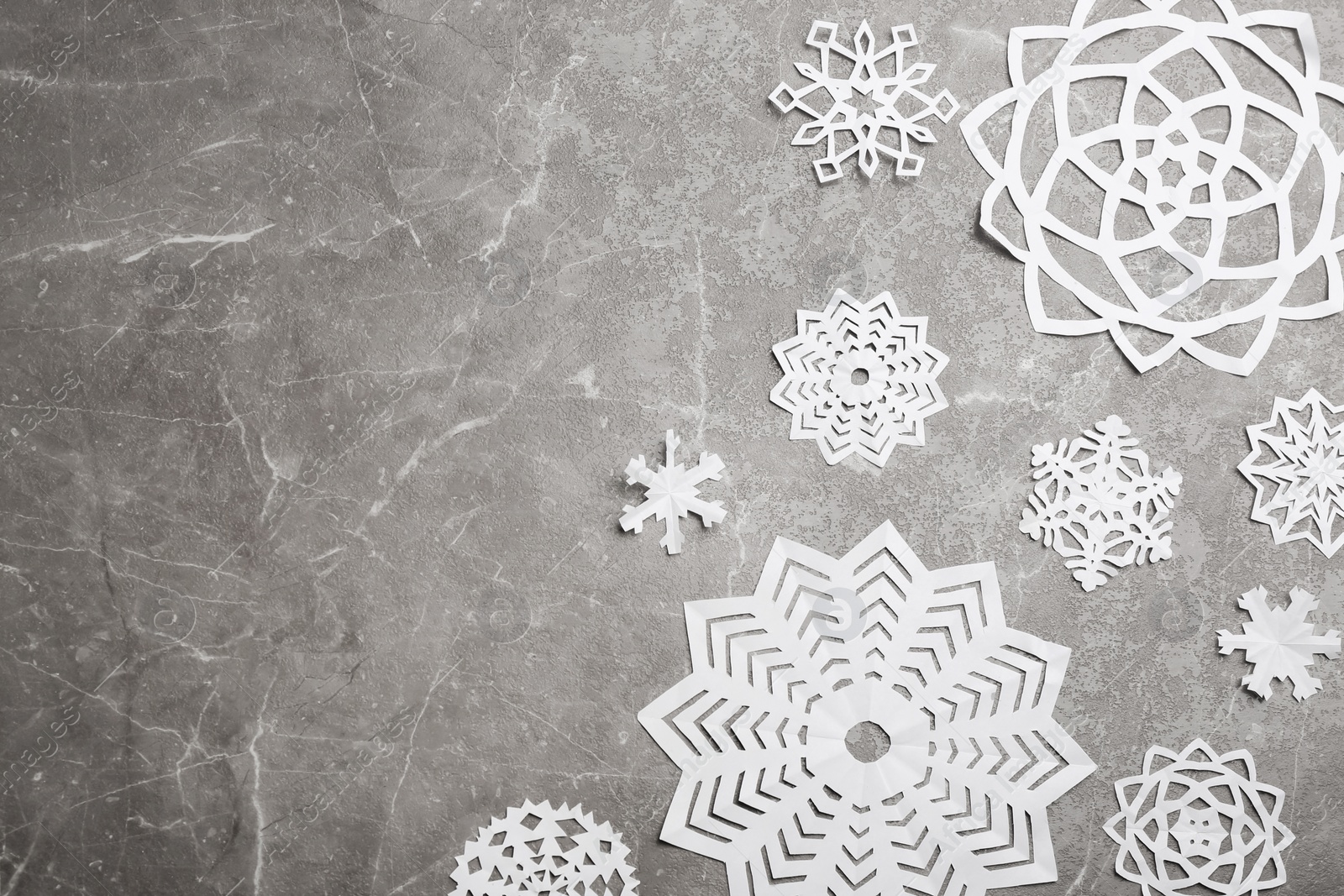 Many paper snowflakes on grey background, flat lay. Space for text Photo of Many paper snowflakes on grey background, flat lay. Space for text