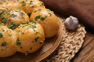 Traditional pampushka buns with garlic and herbs on wooden table, closeup Photo of Traditional pampushka buns with garlic and herbs on wooden table, closeup
