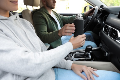 Woman with thermos on passenger seat of car, closeup Photo of Woman with thermos on passenger seat of car, closeup