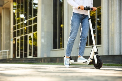 Woman riding electric kick scooter outdoors. Space for text Photo of Woman riding electric kick scooter outdoors. Space for text