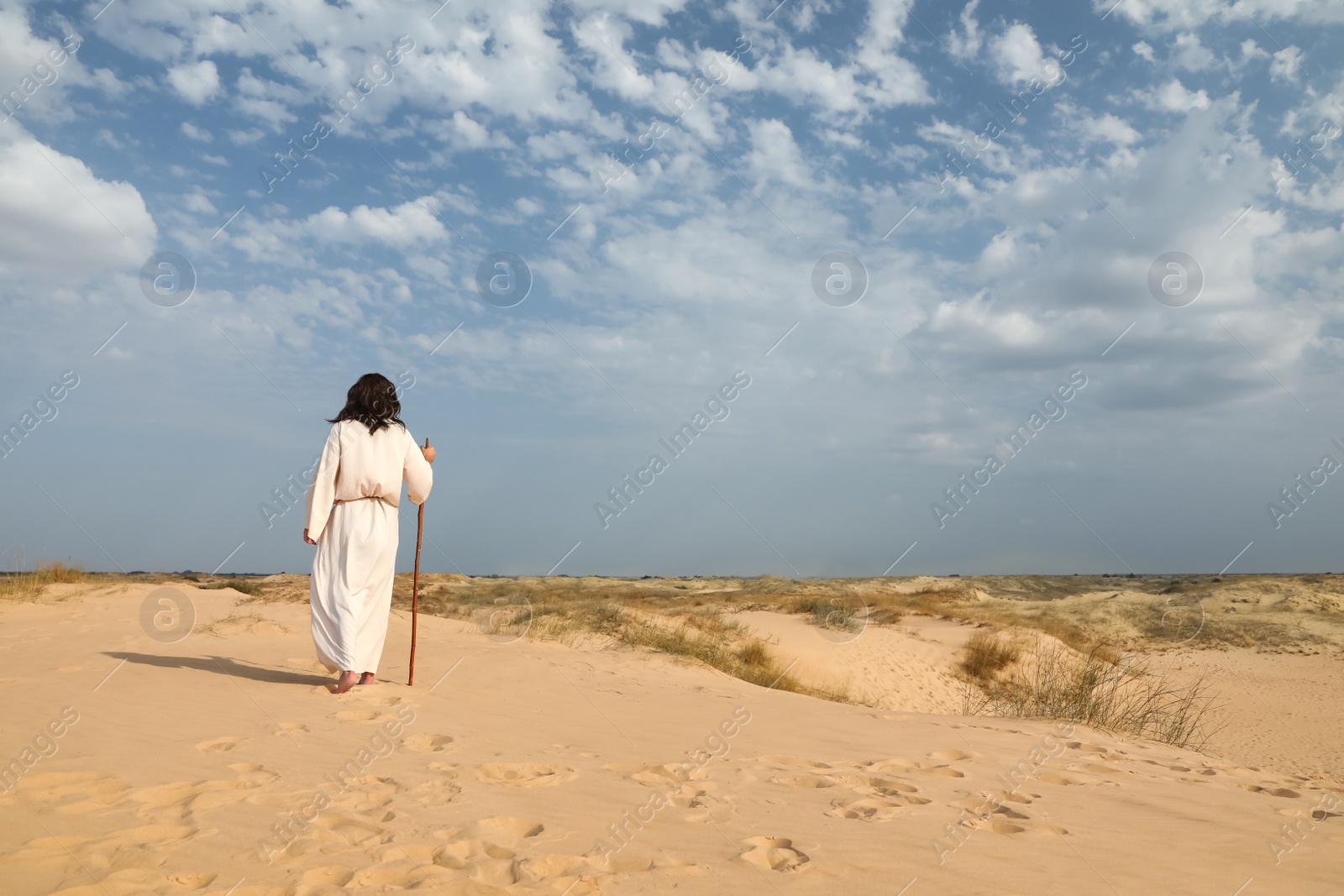 Jesus Christ walking with stick in desert, back view. Space for text Photo of Jesus Christ walking with stick in desert, back view. Space for text