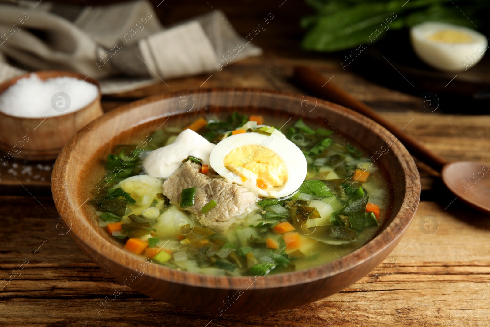 Delicious sorrel soup with meat and egg served on wooden table, closeup Photo of Delicious sorrel soup with meat and egg served on wooden table, closeup