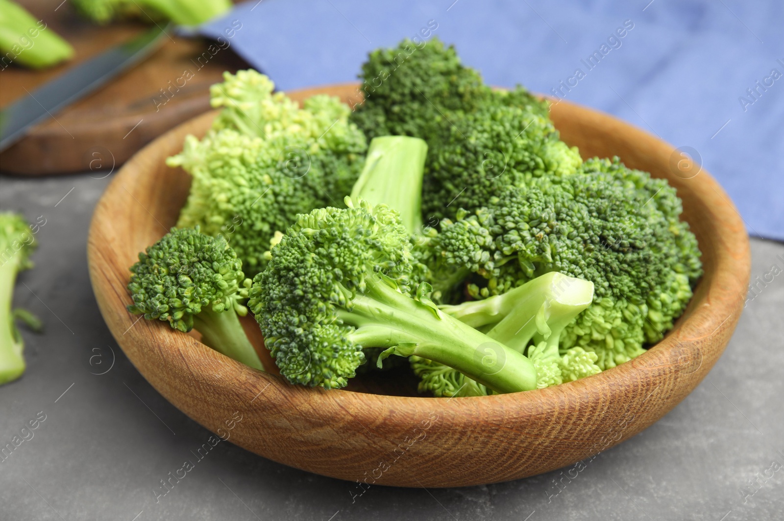 Fresh green broccoli in wooden bowl on grey table, closeup Photo of Fresh green broccoli in wooden bowl on grey table, closeup
