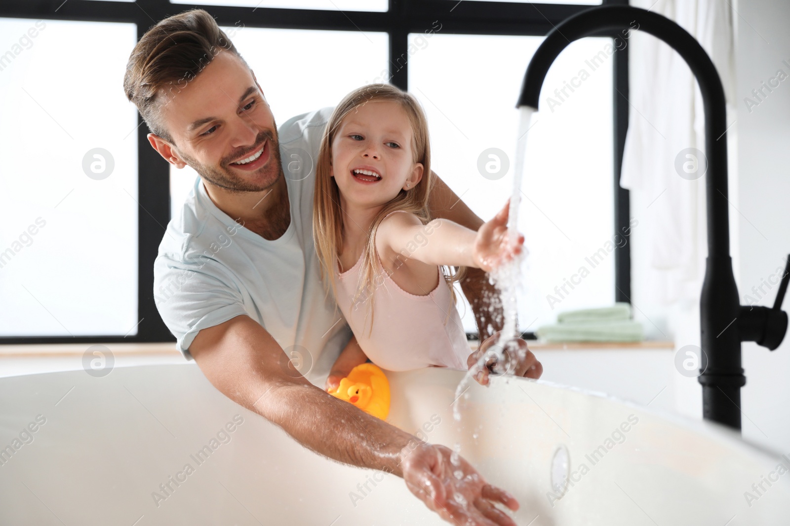 Father with his cute little daughter filling tub in bathroom Photo of Father with his cute little daughter filling tub in bathroom