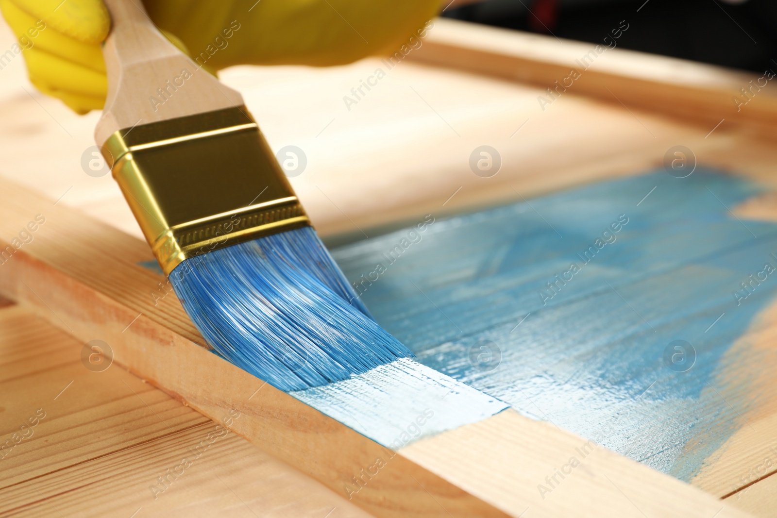 Worker applying blue paint onto wooden surface, closeup. Space for text Photo of Worker applying blue paint onto wooden surface, closeup. Space for text