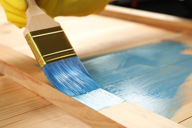 Worker applying blue paint onto wooden surface, closeup. Space for text Photo of Worker applying blue paint onto wooden surface, closeup. Space for text