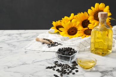 Sunflower oil and seeds on white marble table, space for text Photo of Sunflower oil and seeds on white marble table, space for text