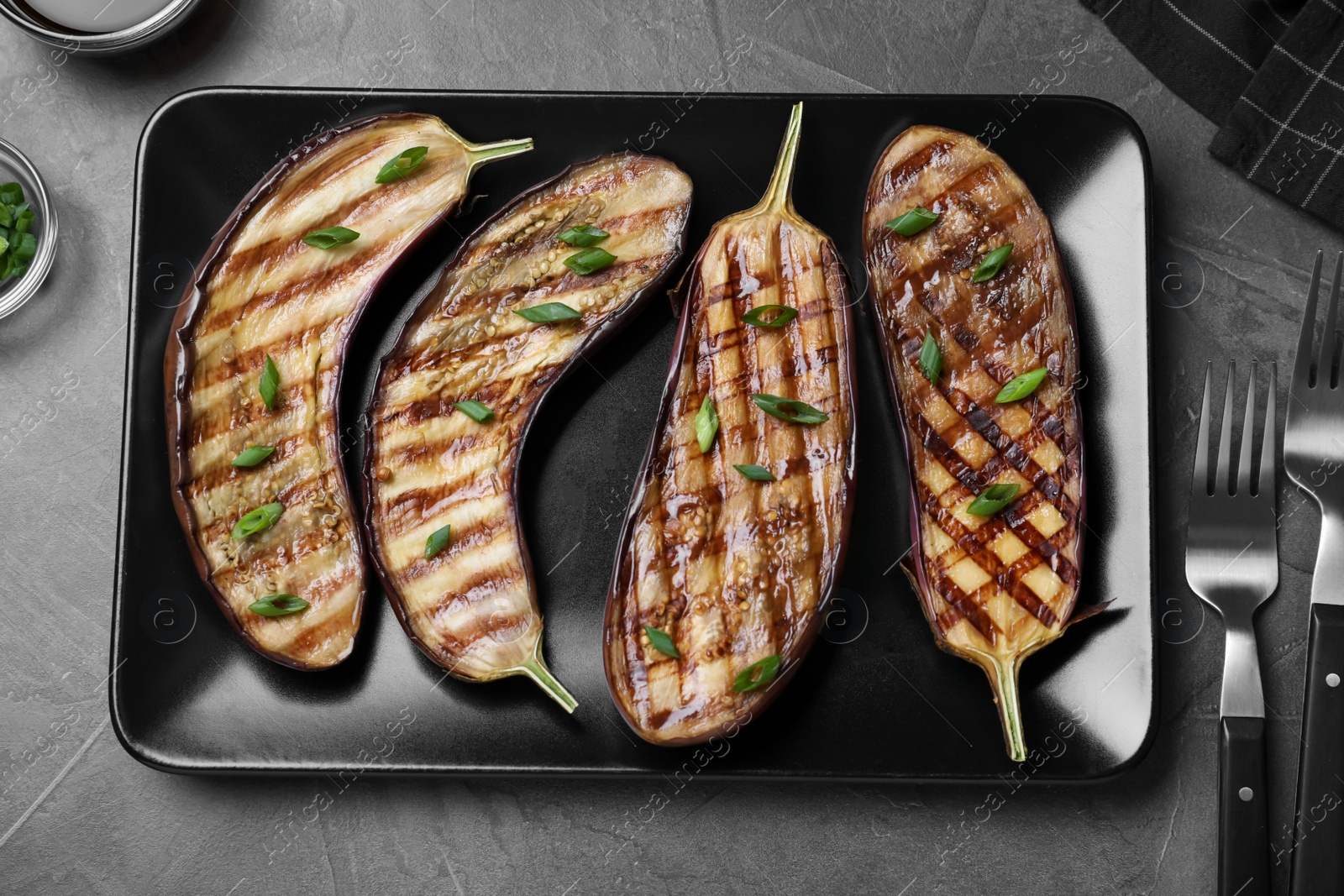 Delicious grilled eggplant halves served on grey table, flat lay Photo of Delicious grilled eggplant halves served on grey table, flat lay
