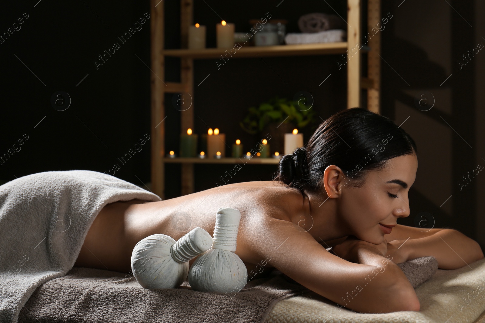 Young woman receiving herbal bag massage in spa salon Photo of Young woman receiving herbal bag massage in spa salon