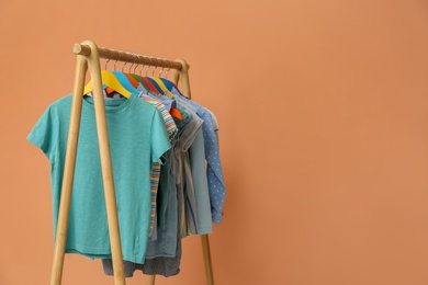 Photo of Rack with stylish children clothes on beige background. Space for text