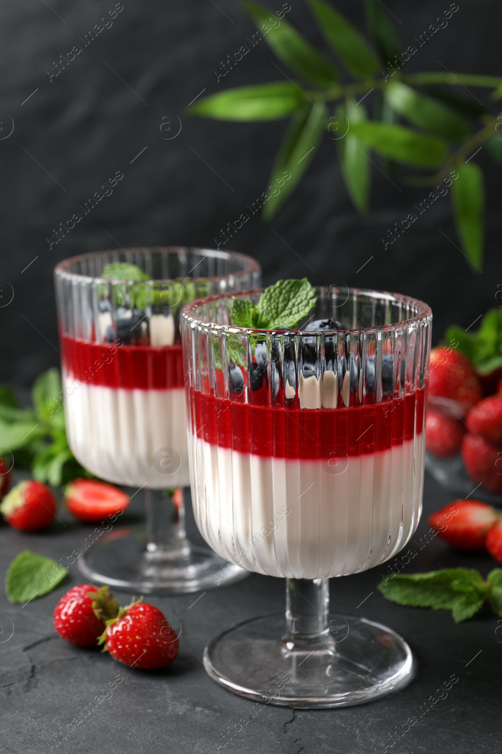 Delicious panna cotta with fruit coulis and fresh berries on dark grey table Photo of Delicious panna cotta with fruit coulis and fresh berries on dark grey table
