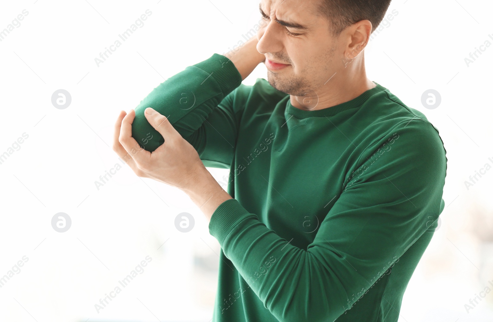 Young man suffering from elbow pain at home Photo of Young man suffering from elbow pain at home