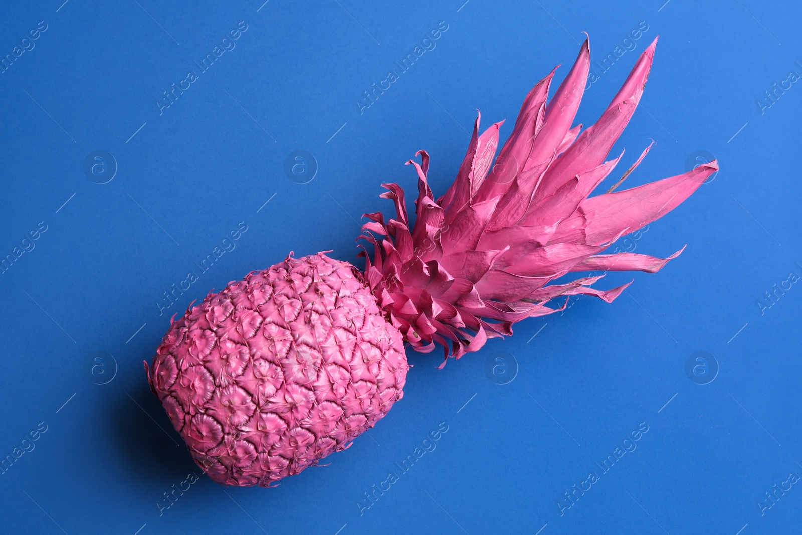 Pink pineapple on blue background, top view. Creative concept Photo of Pink pineapple on blue background, top view. Creative concept