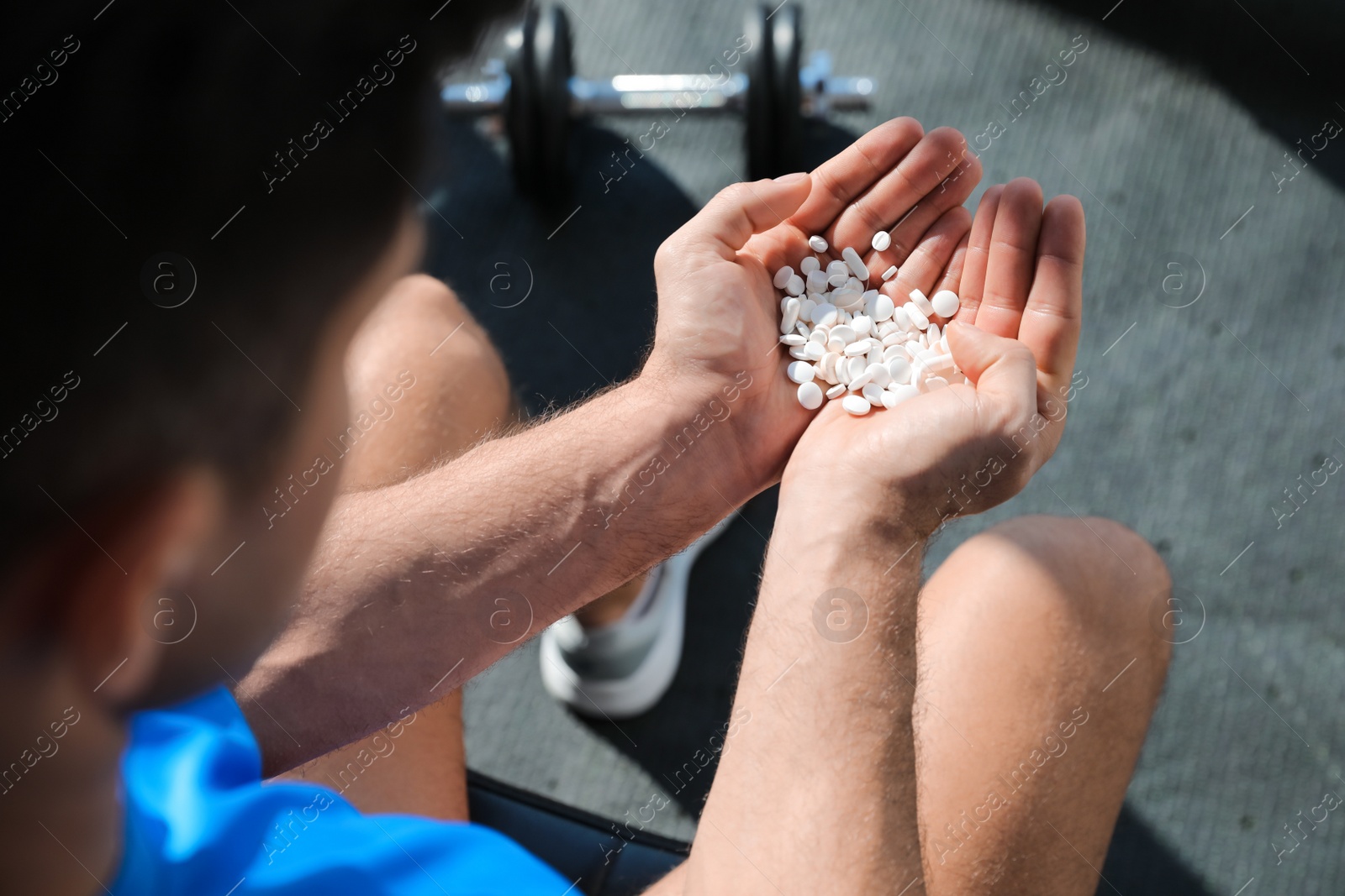 Sportsman with handful of pills in gym, closeup. Doping concept Photo of Sportsman with handful of pills in gym, closeup. Doping concept